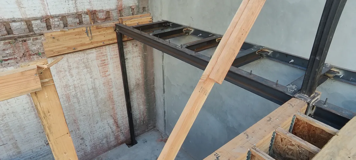 New steel beams and wood floor framing against the original brick wall at Bluxome St