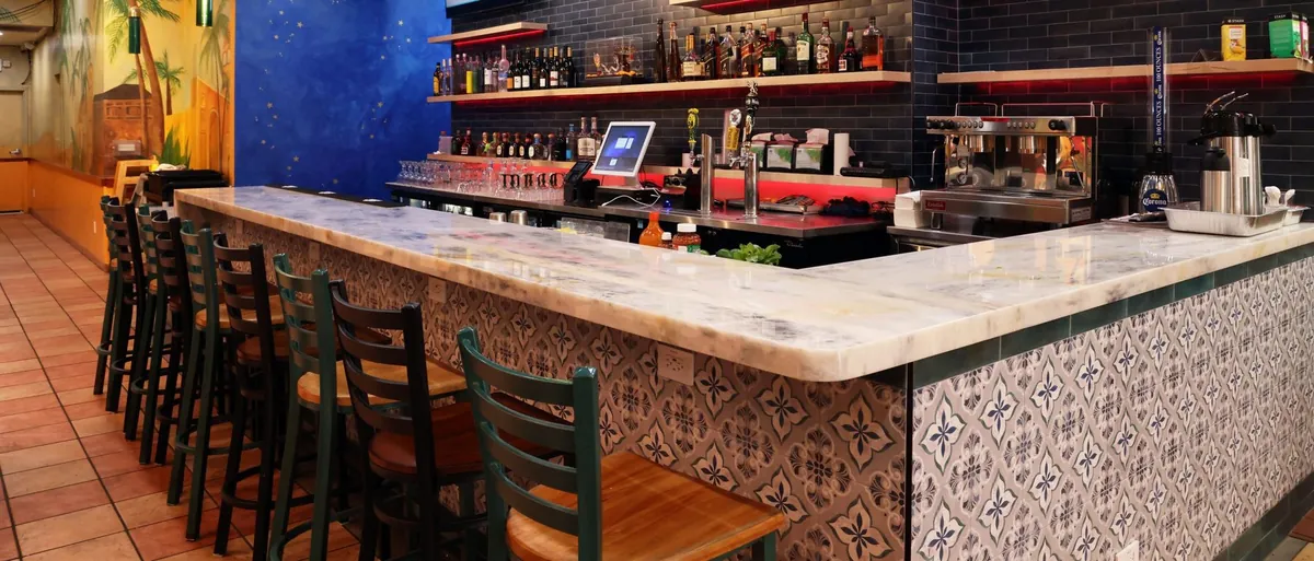 Stone bar top and patterned tile bar front with seating at Mission St